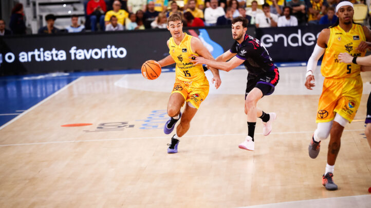 Jugador del Gran Canaria driblando el balón mientras es defendido por un rival.