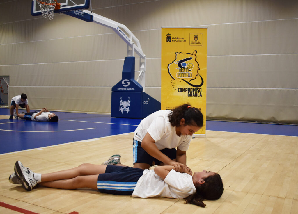 Niña recibiendo primeros auxilios en una cancha de baloncesto durante un evento.