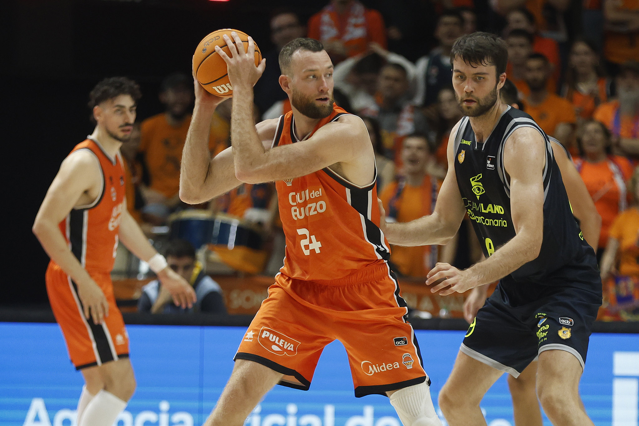 Jugadores de baloncesto en acción, con un jugador del Valencia Basket entre dos del Gran Canaria.