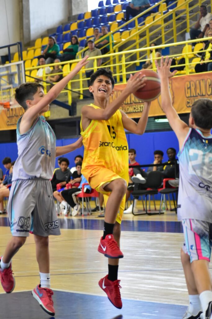 con gran ilusión al Campeonato de Canarias",Jugador preinfantil del Gran Canaria intenta lanzar a la canasta mientras es defendido.
