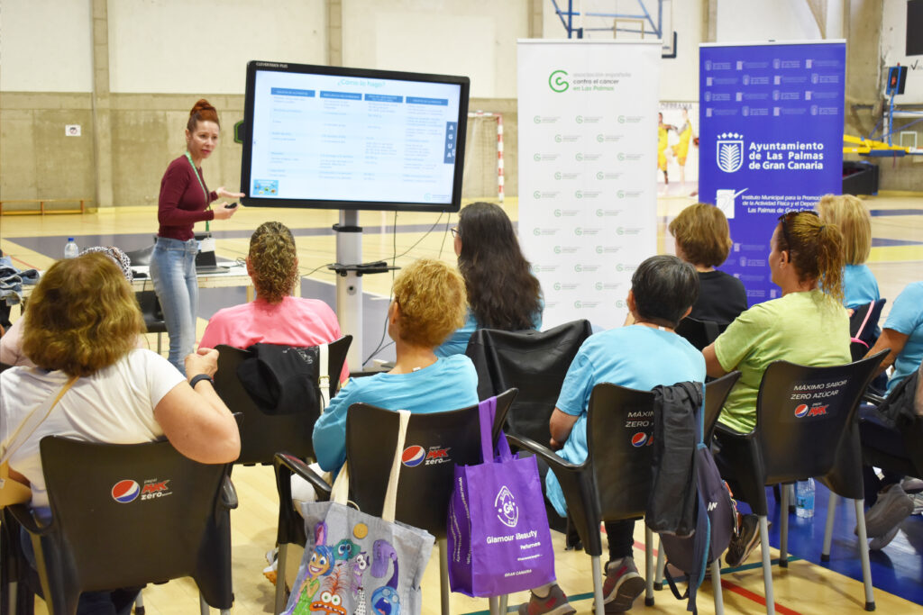 Charla sobre alimentación en el proceso oncológico con asistentes en un gimnasio.