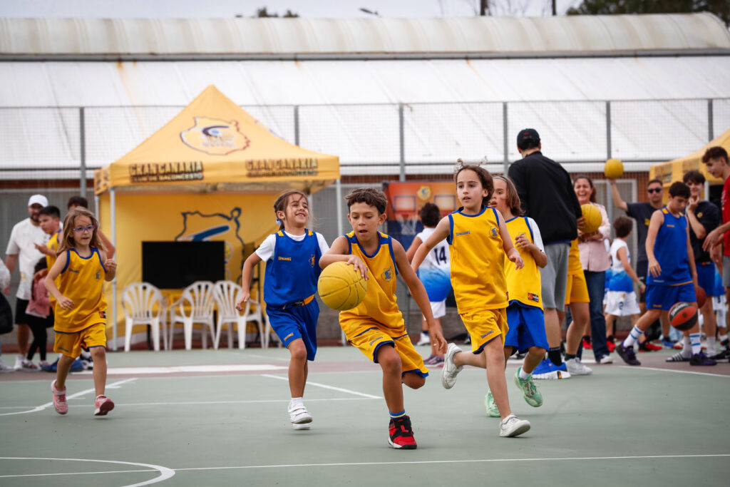 Niños jugando baloncesto en un evento de la Liga Eduardo Polo, con actividades y diversión.