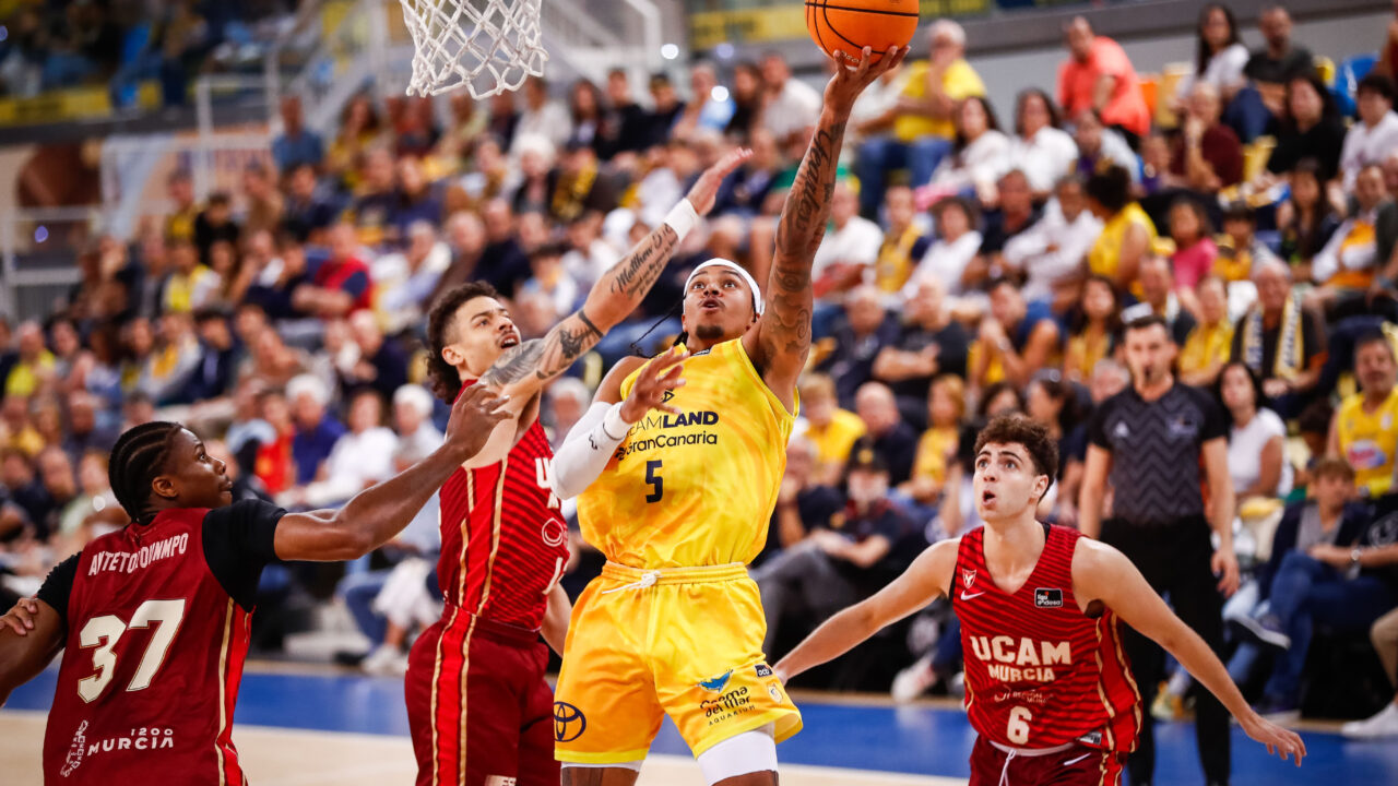 Jugador del Dreamland Gran Canaria lanza a canasta rodeado de defensores del UCAM Murcia.