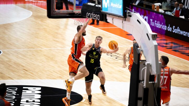 Jugador del Dreamland Gran Canaria lanza a canasta mientras es defendido por oponente.