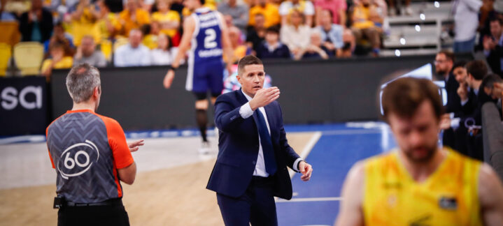 Entrenador dirigiendo al equipo en el banquillo durante un partido de baloncesto.