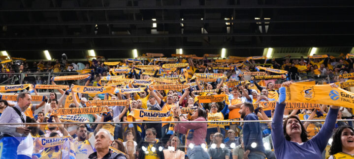 Aficionados del Gran Canaria levantan bufandas animando al equipo en un evento deportivo.