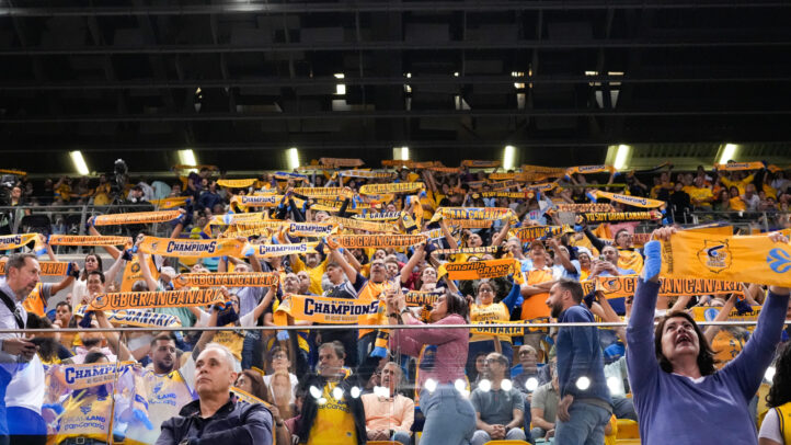 Aficionados del Gran Canaria levantan bufandas animando al equipo en un evento deportivo.