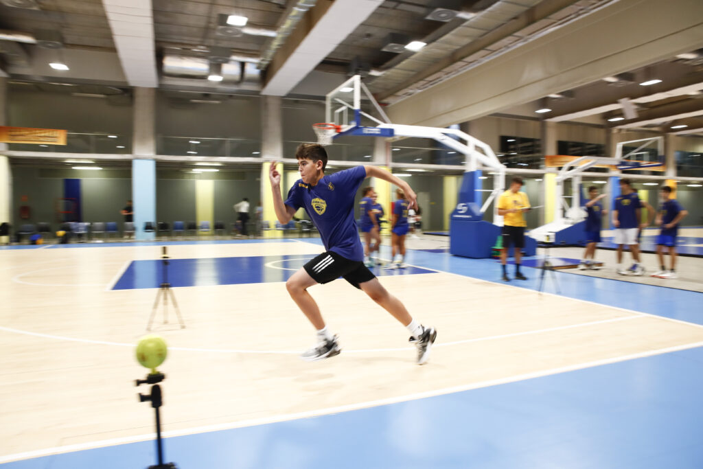 Joven corredor en la cancha durante la CBGC Summer Academy, con entrenadores observando.