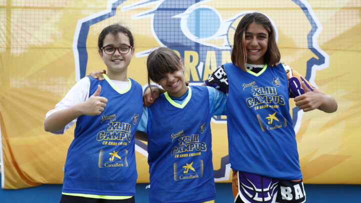 Tres niños sonrientes muestran pulgares hacia arriba, luciendo camisetas del Campus de Verano.