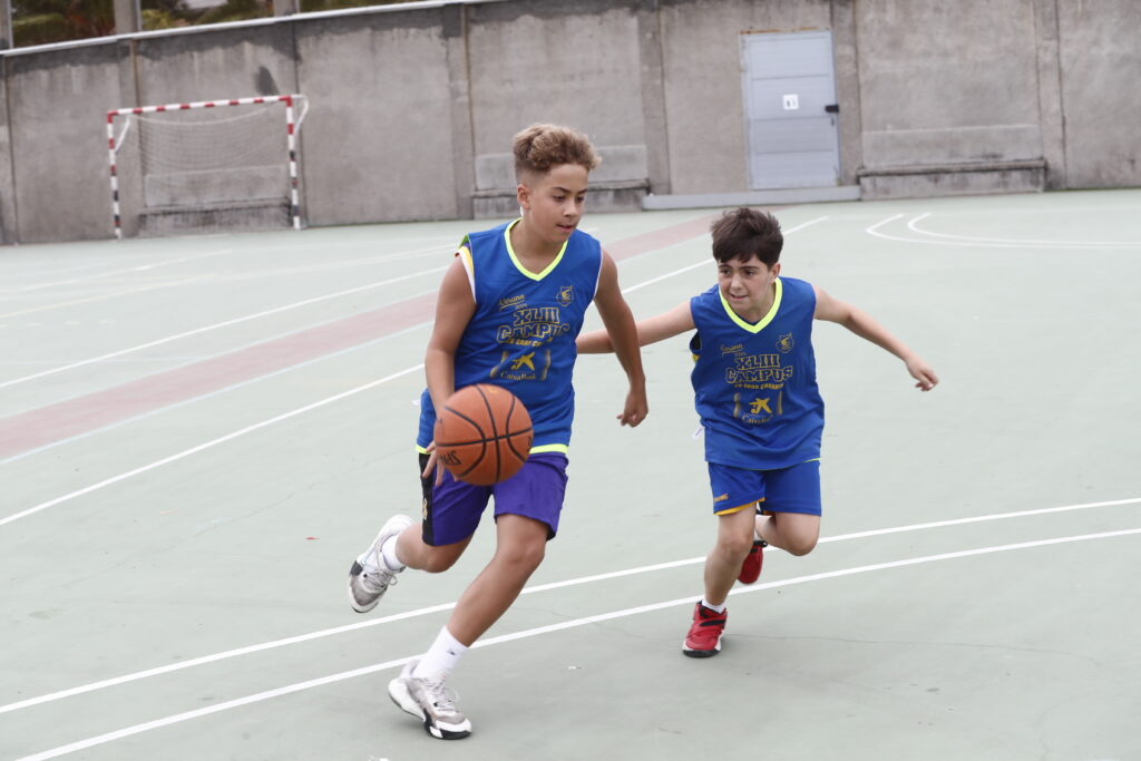 Niños corriendo y jugando al baloncesto en una cancha al aire libre.