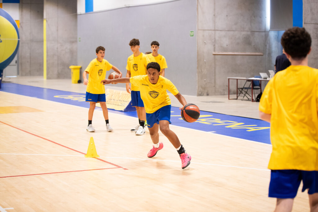 Jugadores entrenando en la II CBGC Summer Academy, practicando con balones en la cancha.