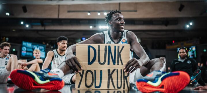 potencia interior para el Dreamland Gran Canaria","Jugadores sonrientes en un evento, con Kur Kuath sosteniendo un cartel que dice ""DUNK YOU KUR"".