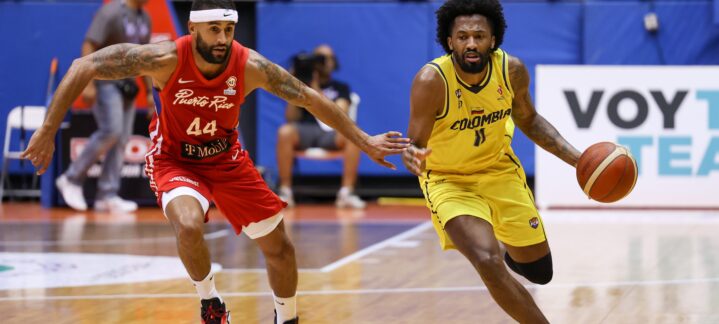 Dos jugadores de baloncesto compiten en la cancha, uno con balón y otro persiguiéndolo.
