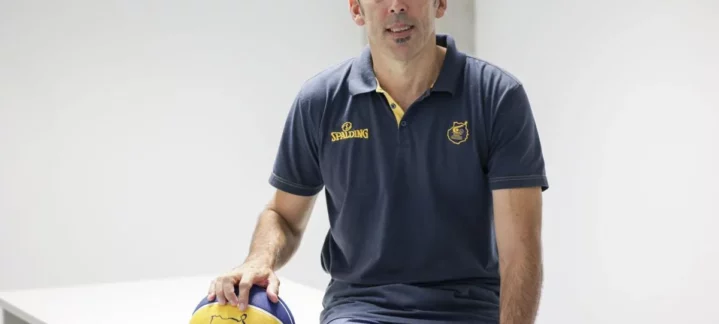 tras el sorteo de la BCL: ""Hay que estar muy atentos desde el principio para tratar de ser primeros""","Willy Villar sentado en una mesa con un balón de baloncesto, en un entorno luminoso.