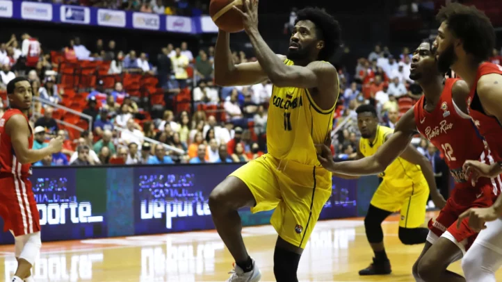 Jugador en acción durante un partido de baloncesto, intentando anotar frente a defensores.
