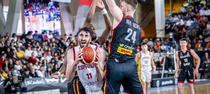 Jugador vestido con la camiseta de España defendido por rivales en un partido de baloncesto.