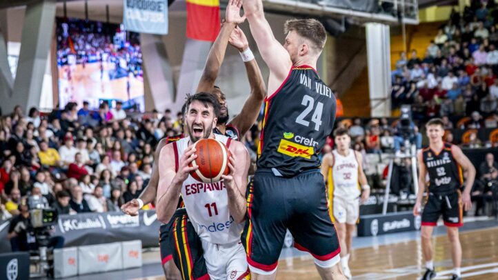 Jugador vestido con la camiseta de España defendido por rivales en un partido de baloncesto.