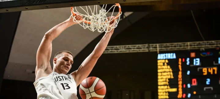 Jugador en acción, encestando en un partido internacional de baloncesto.