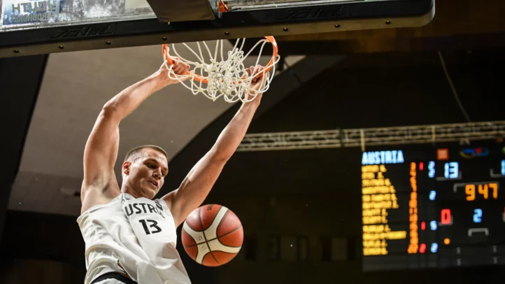 Jugador en acción, encestando en un partido internacional de baloncesto.
