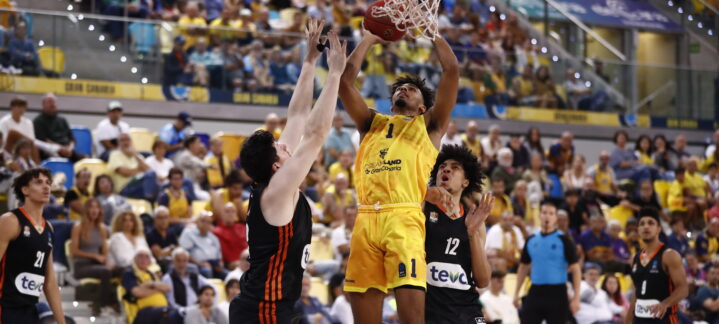 Jugador en acción intentando encestar durante un partido de baloncesto.