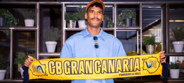 Jugador sostiene una bufanda del CB Gran Canaria en un ambiente interior.