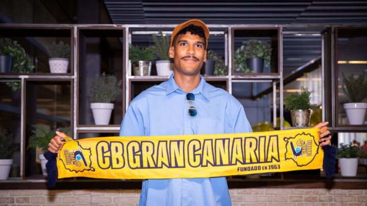 Jugador sostiene una bufanda del CB Gran Canaria en un ambiente interior.