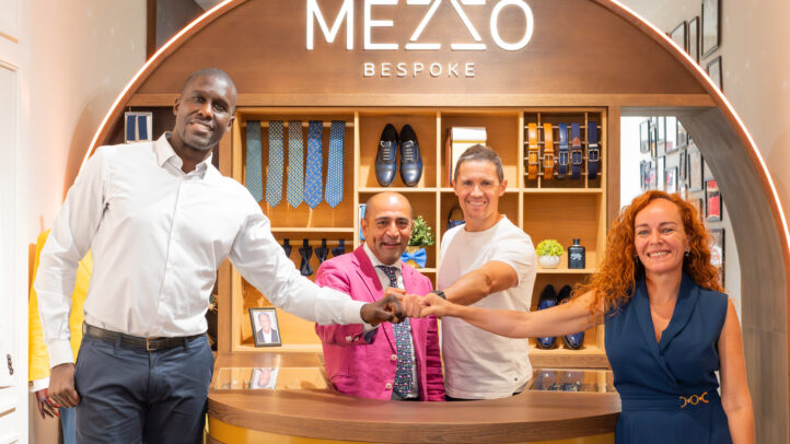 Cuatro personas posan en una tienda de Mezzo Bespoke con accesorios y zapatos de fondo.