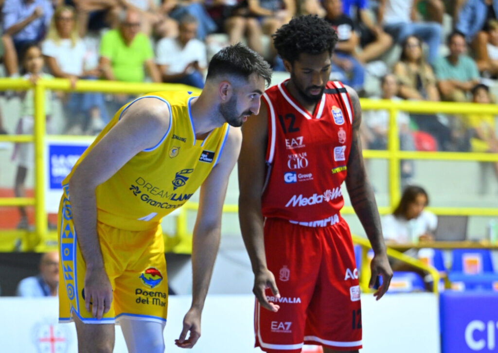 Dos jugadores de baloncesto en el campo, uno con camiseta amarilla y el otro en rojo.