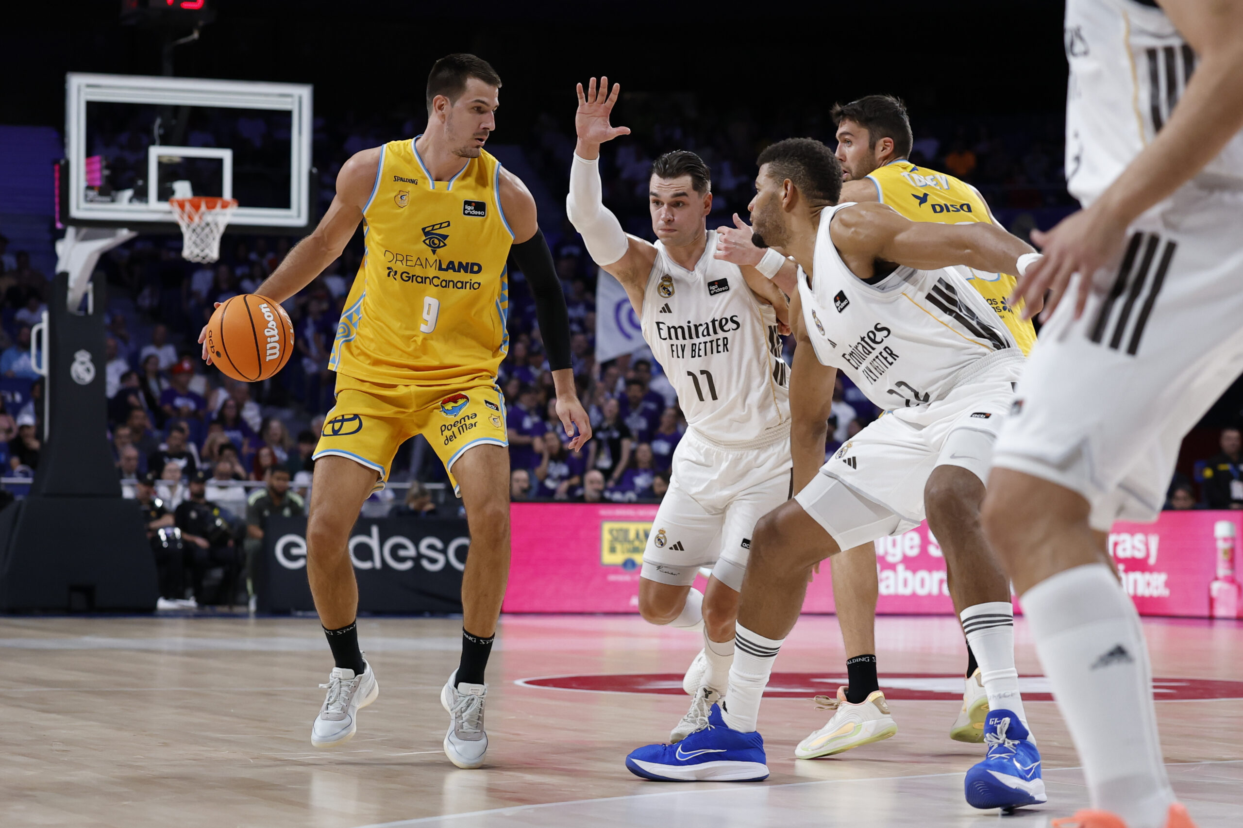 Jugador del Club Baloncesto Gran Canaria driblando ante defensores del equipo rival.