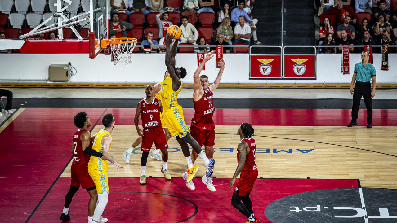 Jugador del Gran Canaria lanza a canasta mientras es defendido por oponentes.