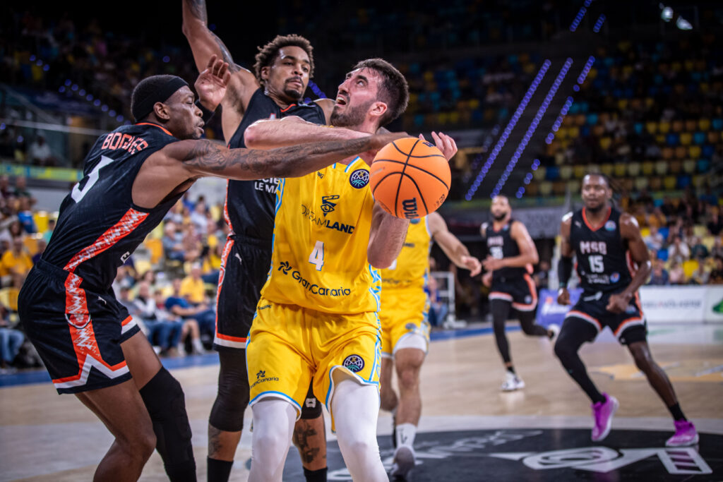 Jugador del Dreamland Gran Canaria intenta anotar mientras es defendido por rivales.
