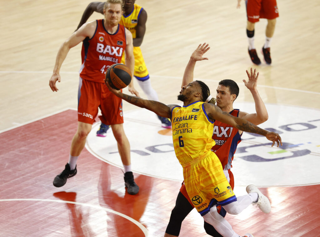 Jugador del Gran Canaria realiza una jugada mientras es defendido por oponente.