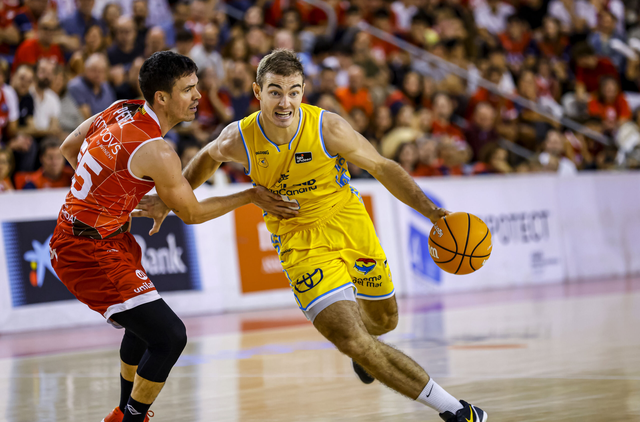 Jugador del Club Baloncesto Gran Canaria avanza con el balón, defendido por un rival.