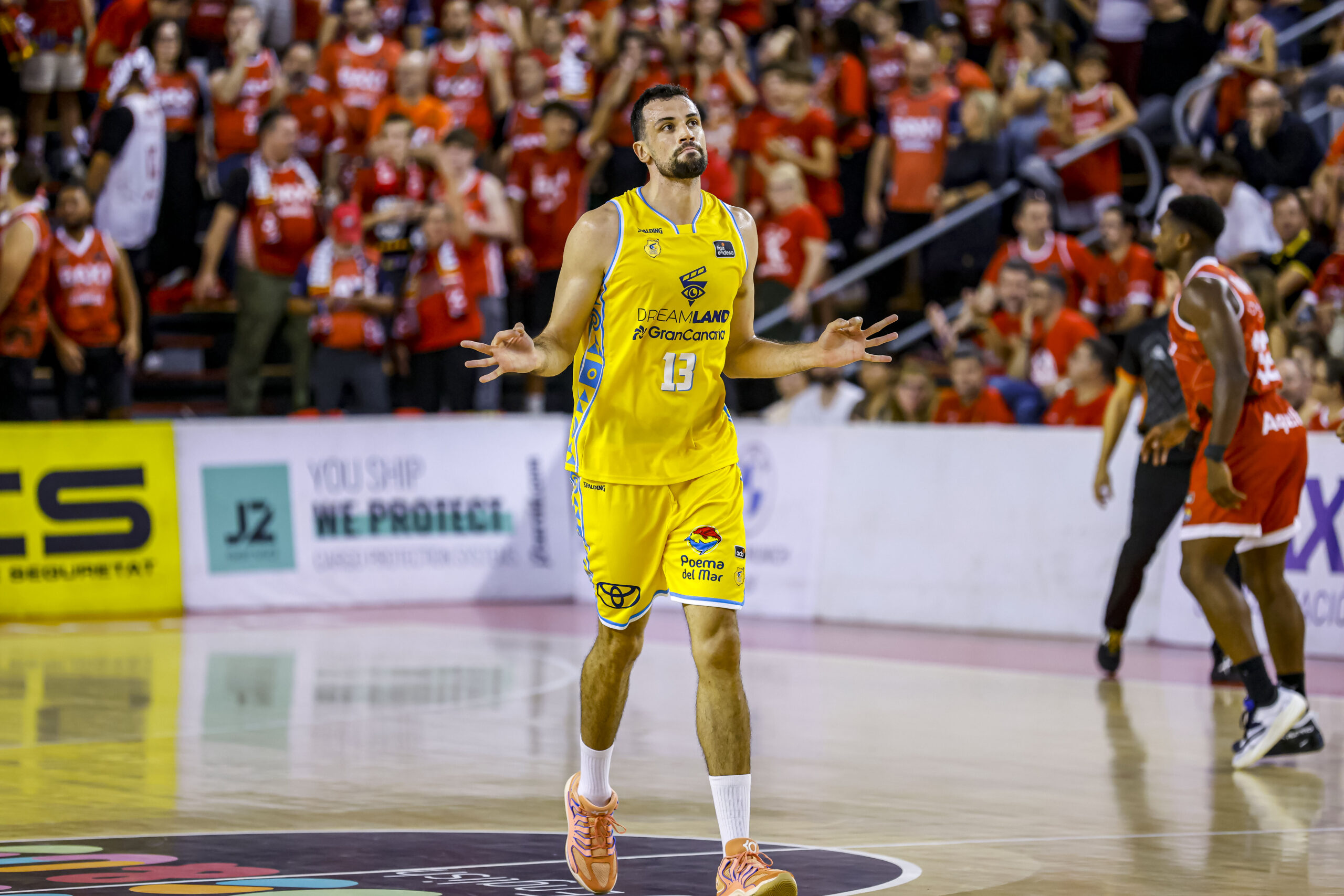 Jugador del Gran Canaria celebra en la cancha, con público animando de fondo.